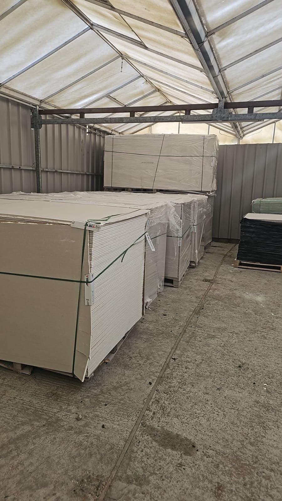 Shrink-wrapped pallets of plasterboard sheets in a warehouse