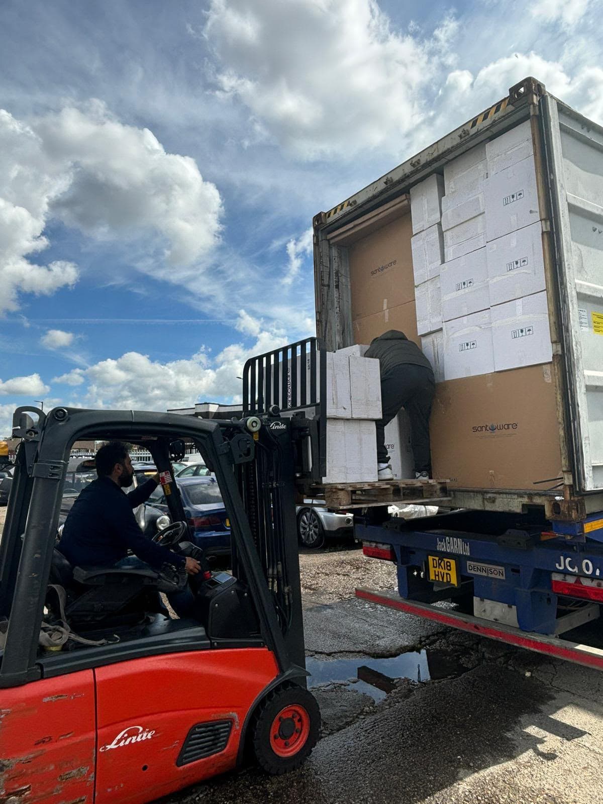 Forklift unloading boxes of sanitaryware from a shipping container